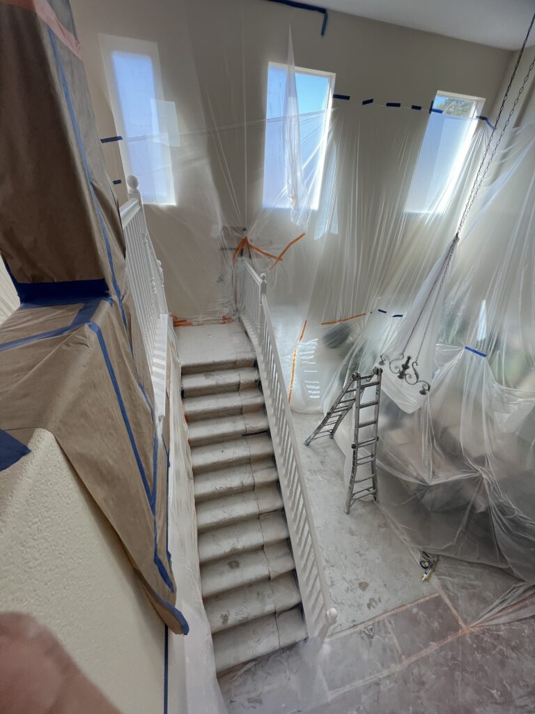 Bright and open living area with staircase painted by Monarch Painting in San Diego, featuring neutral tones and smooth finishes.