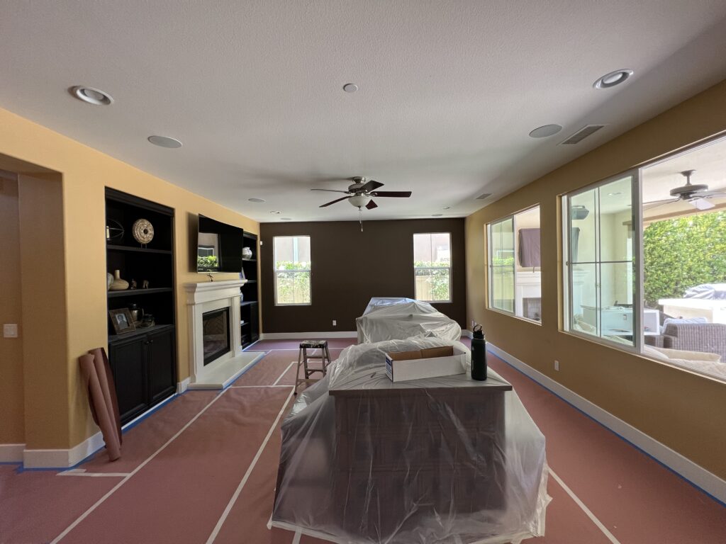 iving area prepped for painting by professional house painters in Carlsbad with floors and furniture protected.