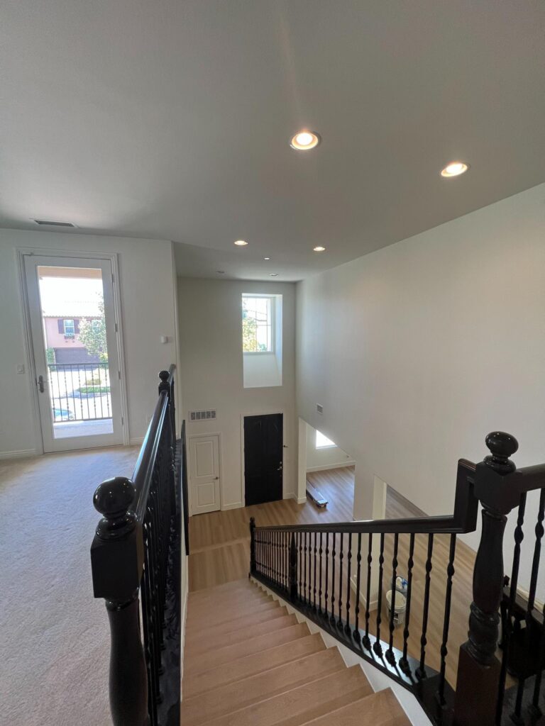 Elegant staircase interior painting in San Diego by Monarch Painting with white risers and a black handrail.